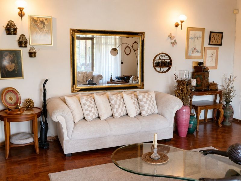 A living room featuring classic parquet flooring and wall-mounted lighting fixtures, offering a traditional layout with access to an adjacent space.