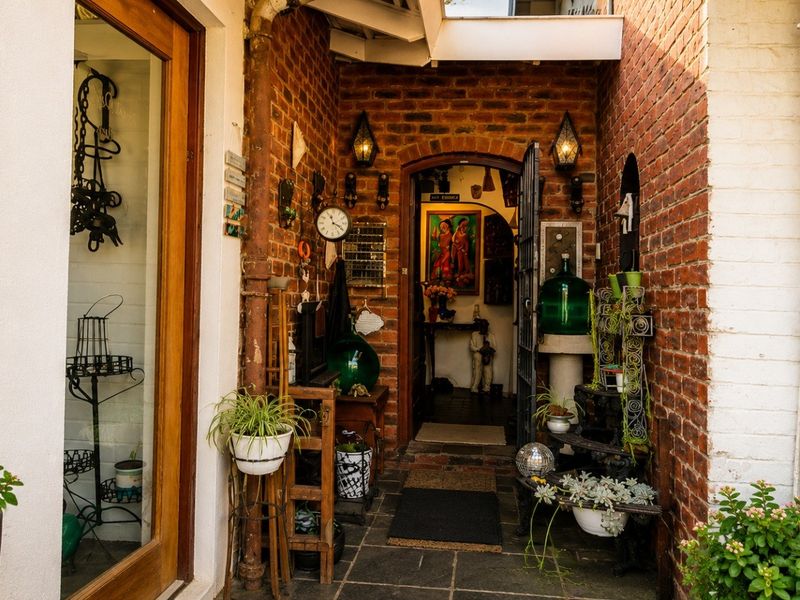 A charming, rustic entrance area featuring exposed brick walls, stone tile flooring, and a timber-framed glass door leading into the home.