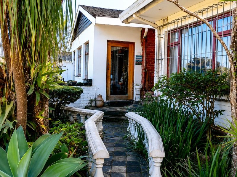 Front entrance featuring a stone paved walkway with decorative balustrades, leading to a timber framed door with security bars on the windows.