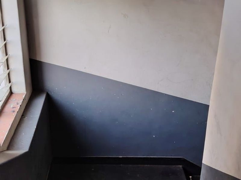 A view of an interior staircase with painted walls and a window, showing signs of wear and requiring cosmetic maintenance.