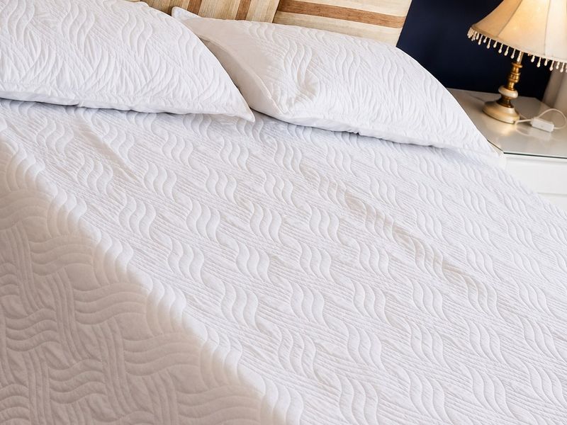 A close-up view of a bedroom featuring a textured headboard and bedding.