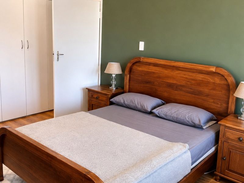 A well-maintained bedroom featuring laminate flooring, built-in cupboards, and a feature wall with recessed downlighting.