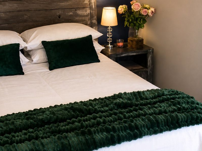 A cozy bedroom featuring a dark blue accent wall and neutral tones, creating a comfortable and inviting sleeping space.