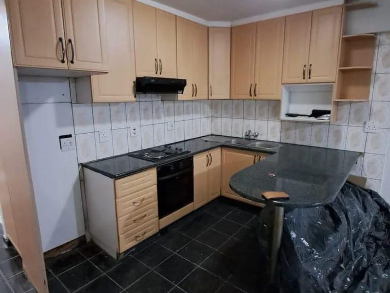 A functional kitchen featuring light wood cabinetry, granite countertops, a breakfast bar, and integrated appliances, ready for a modern update.