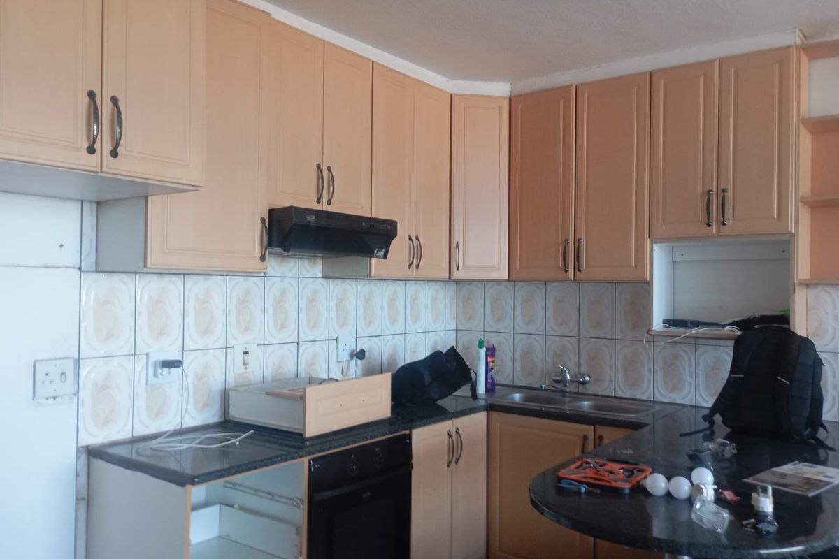 A dated kitchen featuring laminate cabinetry, granite countertops, a built-in oven, and a tiled backsplash, requiring minor repairs and cosmetic updates.