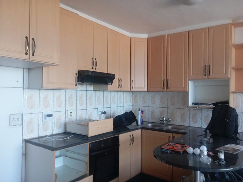A dated kitchen featuring laminate cabinetry, granite countertops, a built-in oven, and a tiled backsplash, requiring minor repairs and cosmetic updates.