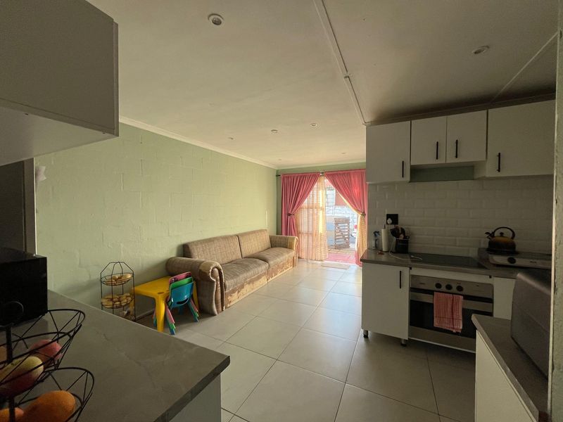 Open-plan living area featuring a functional kitchen with built-in cabinetry and appliances, tiled flooring, and direct access to an outdoor patio space.