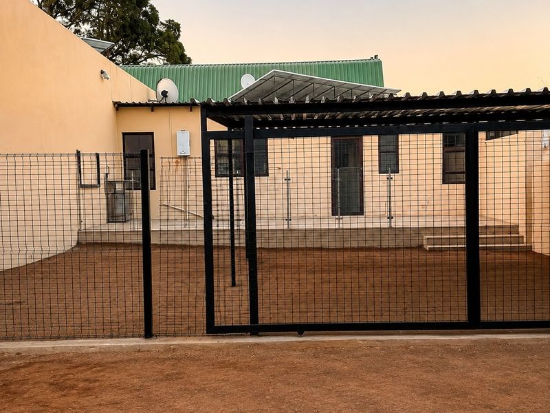 Rear exterior view featuring a fenced yard area, covered patio space, and functional utility installations including a gas geyser.