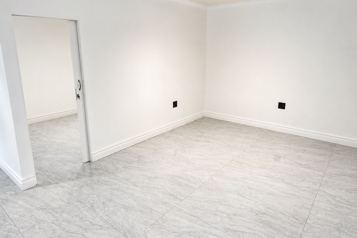 A bright, empty living space featuring modern grey marble-look porcelain floor tiles, crisp white walls, and contemporary track lighting.