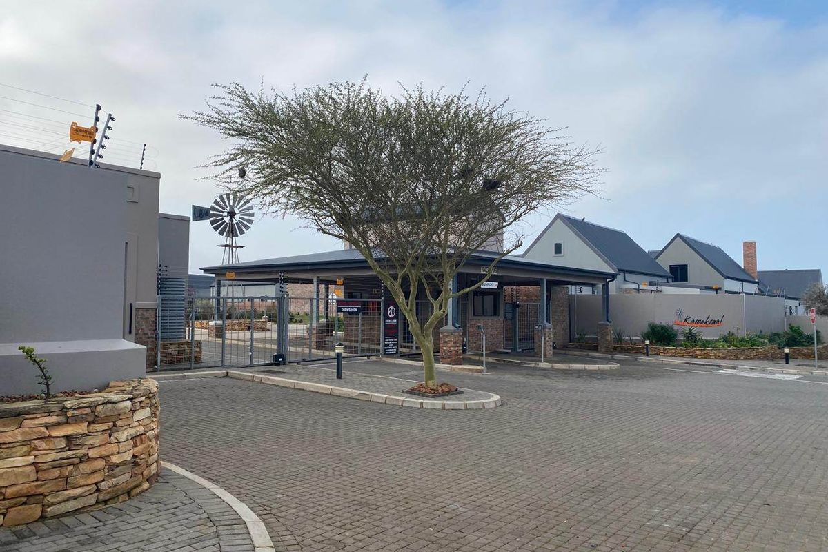 The entrance to the Karookraal estate features a paved driveway, security gatehouse, and perimeter electric fencing, presenting a well-maintained and secure access point.