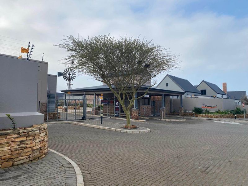 The entrance to the Karookraal estate features a paved driveway, security gatehouse, and perimeter electric fencing, presenting a well-maintained and secure access point.
