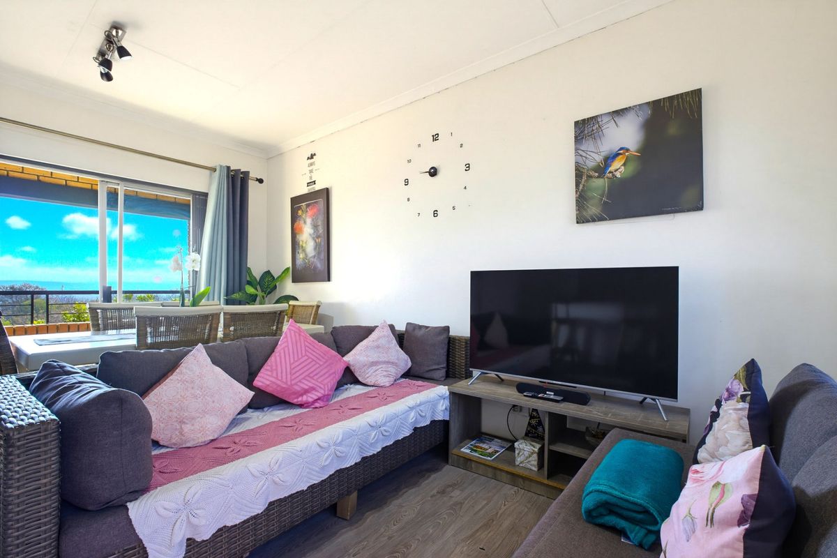 A comfortable living room area featuring laminate flooring, track lighting, and a large sliding glass door providing access to the outdoor patio space.