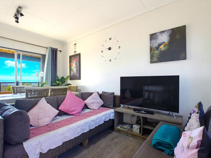A comfortable living room area featuring laminate flooring, track lighting, and a large sliding glass door providing access to the outdoor patio space.