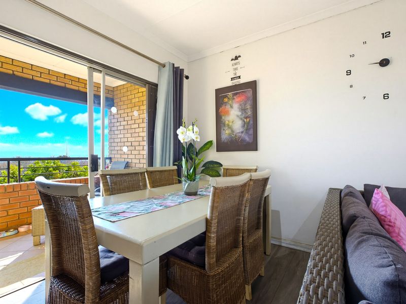 Open plan dining area featuring laminate flooring and large sliding glass doors leading to a private balcony with brick wall detailing.