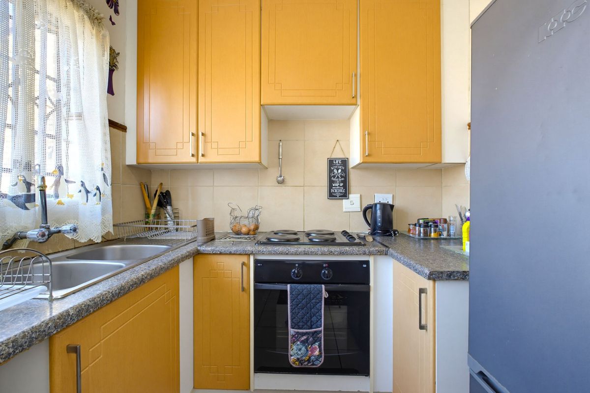 Compact kitchen featuring yellow built-in cabinetry, laminate countertops, a double basin sink, and a built-in electric oven with hob.