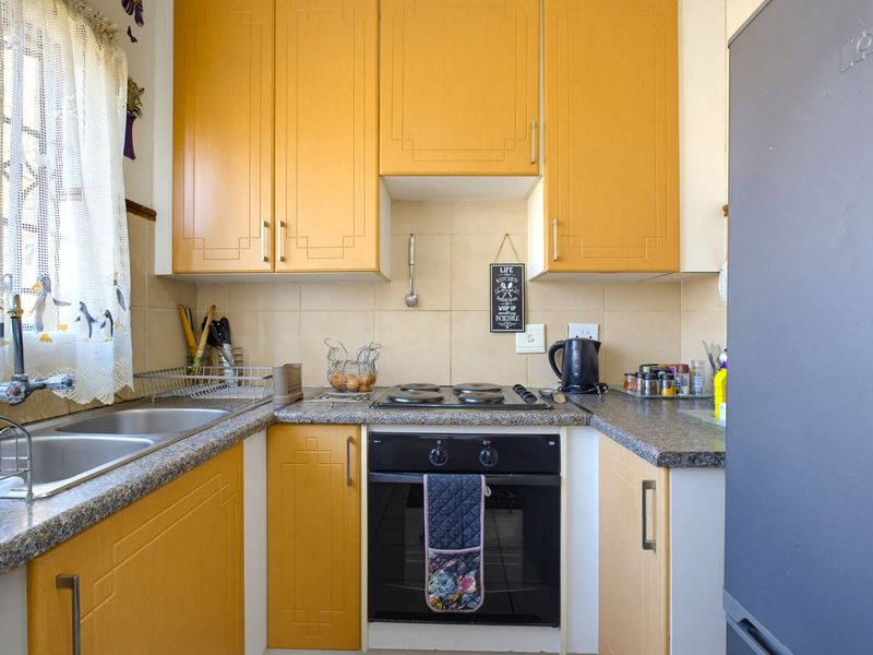 Compact kitchen featuring yellow built-in cabinetry, laminate countertops, a double basin sink, and a built-in electric oven with hob.