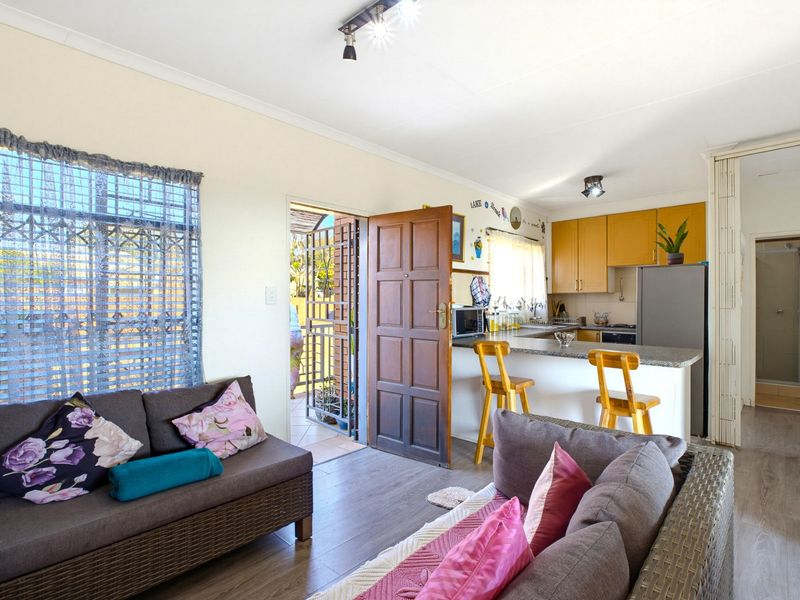 Open plan living area featuring a functional kitchen with granite countertops, laminate flooring, and direct access to the exterior through a secure entrance door.