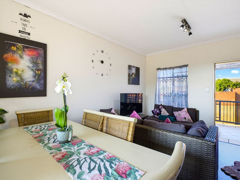 Open plan living and dining area featuring tiled flooring, ceiling mounted lighting, and direct access to an outdoor balcony space.