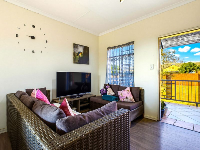 A cozy living room featuring laminate flooring and direct access to an outdoor balcony through a secure door.