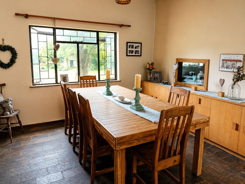 A dining room featuring tiled flooring, built-in wooden cabinetry, and a large leaded glass window overlooking the garden.