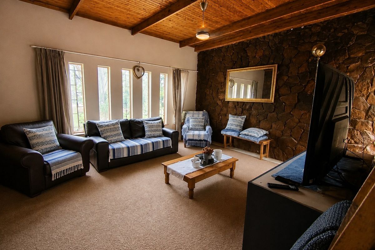 A cozy living room featuring a rustic stone accent wall, exposed timber beam ceiling, and large vertical windows that provide natural light.