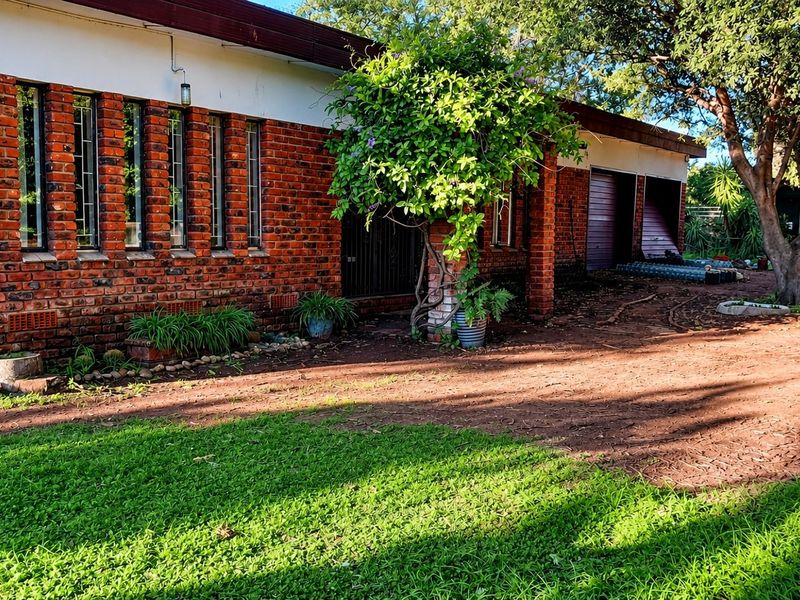 Front exterior view of a face brick house featuring vertical windows and a double garage with visible damage to the garage door.