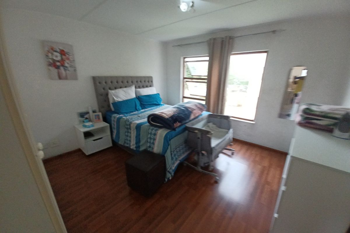 A bedroom featuring laminate flooring, natural light from casement windows, and a standard ceiling light fixture.