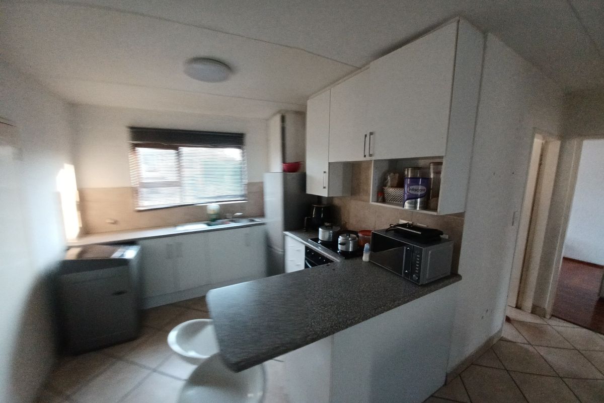 Functional kitchen featuring built-in cabinetry, laminate countertops, a breakfast bar, and tiled flooring, offering a practical layout for daily meal preparation.