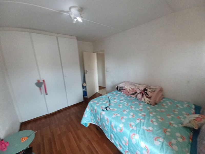 A functional bedroom featuring laminate flooring and a built-in wardrobe, providing essential storage space within the apartment.