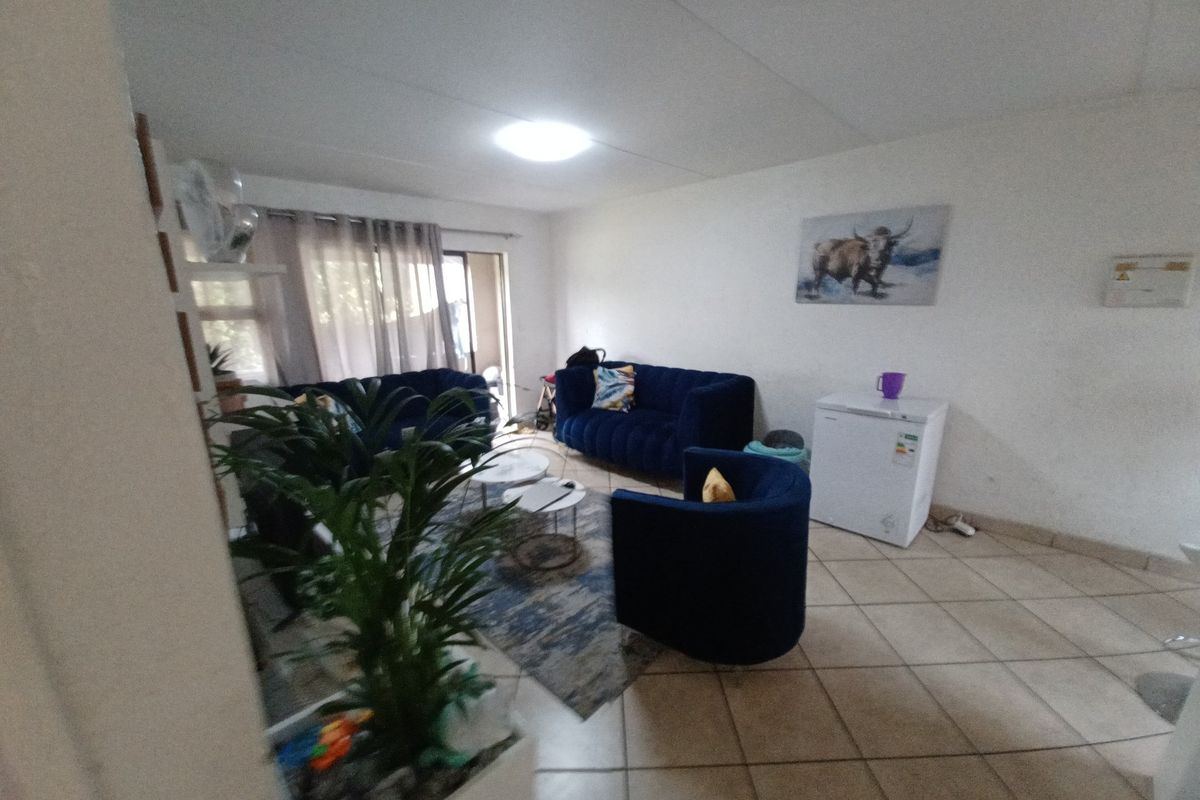 A living room area featuring tiled flooring and a sliding glass door leading to an outdoor space.