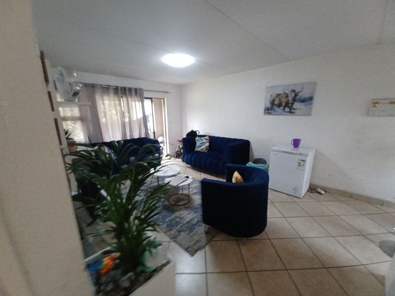 A living room area featuring tiled flooring and a sliding glass door leading to an outdoor space.