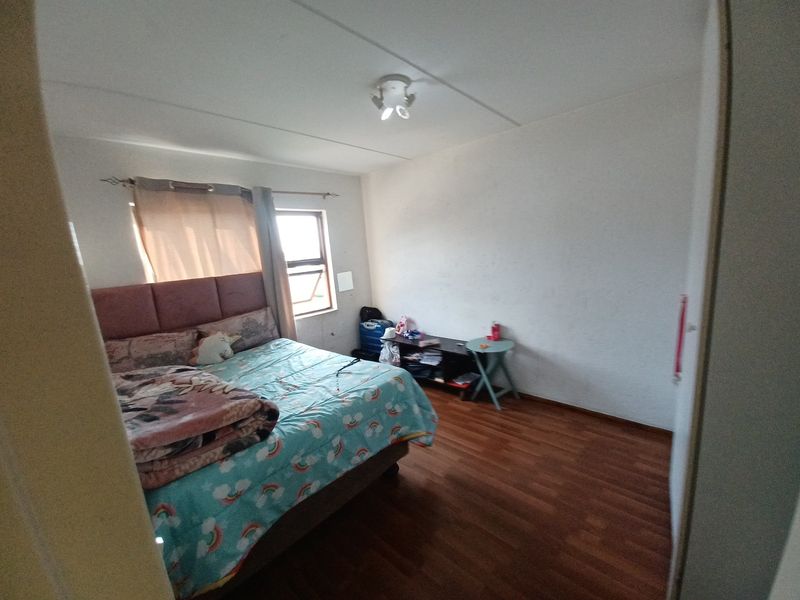 A standard bedroom featuring laminate flooring, a central ceiling light, and a window, providing a functional space with potential for cosmetic updates.