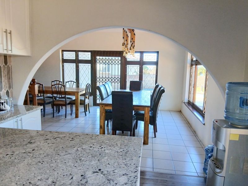 Open plan kitchen and dining area featuring granite countertops, tiled flooring, and a distinctive architectural archway connecting the spaces.