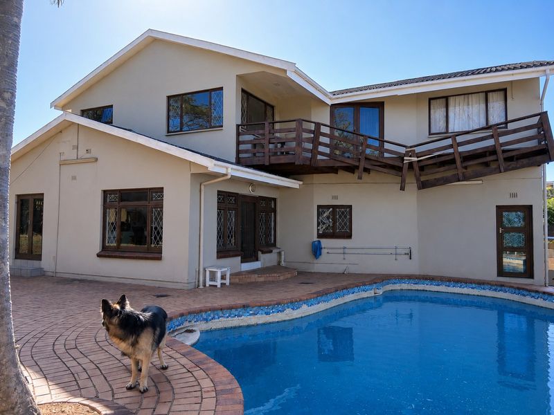 Rear exterior view of a townhouse featuring a swimming pool, paved patio area, and an elevated wooden balcony with visible structural wear.