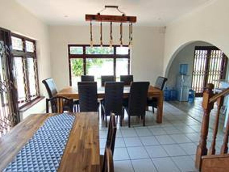 Spacious dining area featuring tiled flooring, an architectural archway, and a wooden staircase, providing a functional layout for family meals and entertaining.