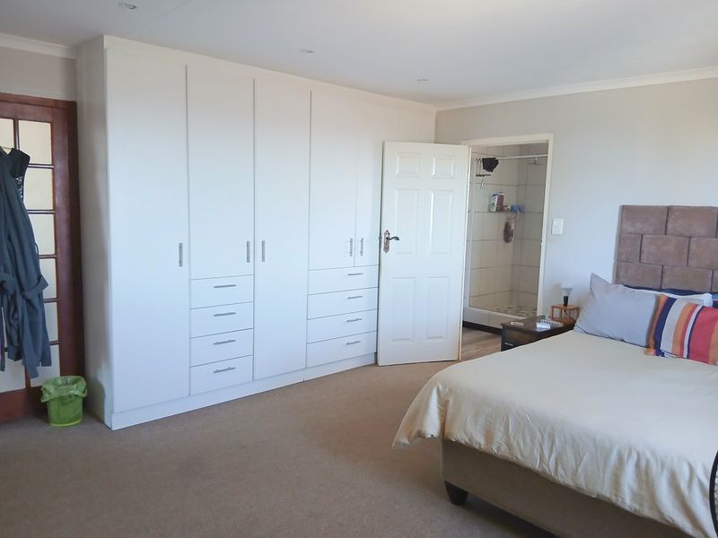 Spacious bedroom featuring extensive built-in cupboards, neutral carpeting, recessed lighting, and direct access to an en-suite bathroom.