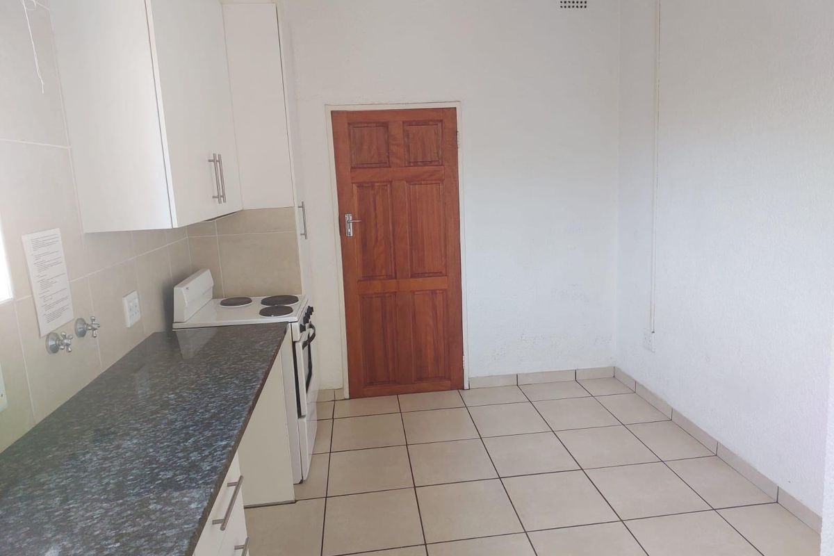 A functional kitchen featuring white cabinetry, granite countertops, a freestanding stove, and tiled flooring, offering a clean and practical space.