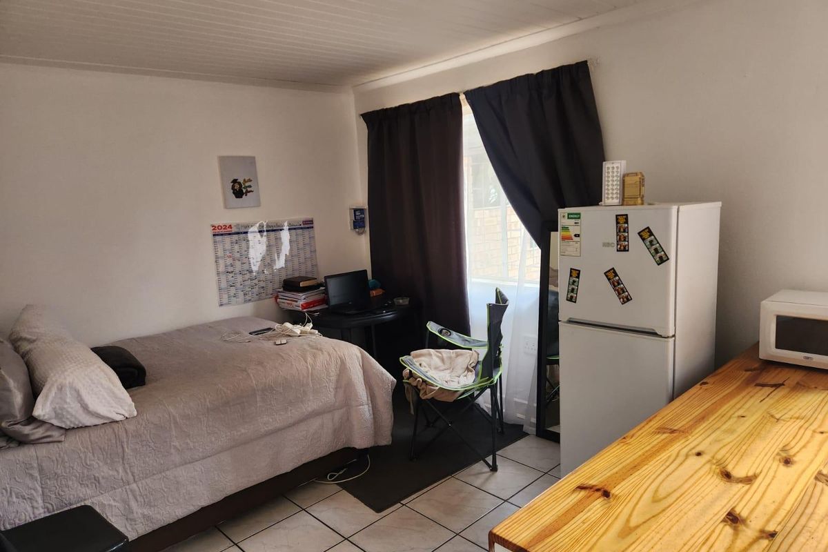 A functional bedroom featuring tiled flooring and a timber ceiling, currently utilized as a multi-purpose living space.