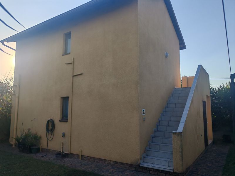 Side view of the property featuring an external staircase with tiled steps and a plastered exterior finish.