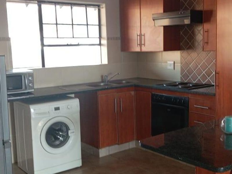A functional kitchen featuring wood-finish cabinetry, granite countertops, a breakfast nook, and integrated appliances including an oven, hob, and extractor fan.