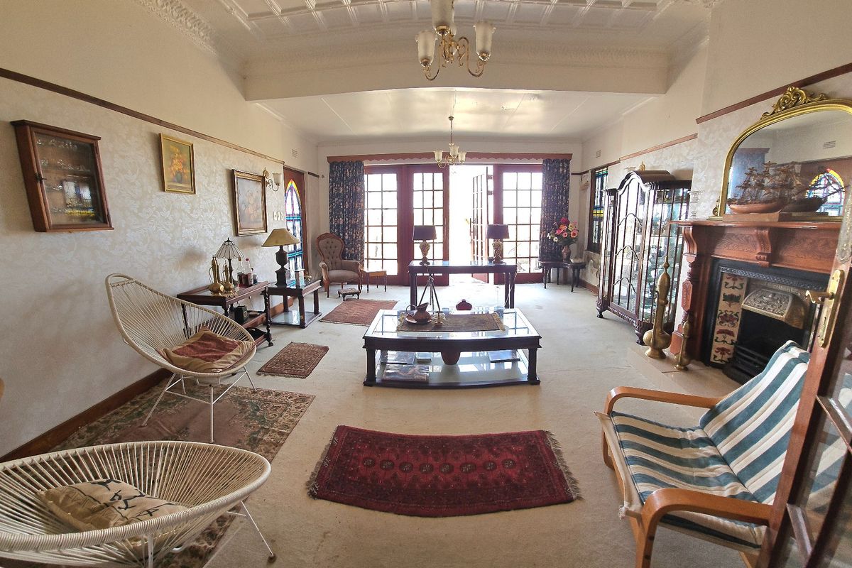 Spacious living room featuring a classic fireplace with timber mantel, ornate ceiling cornicing, and double french doors leading to the exterior.