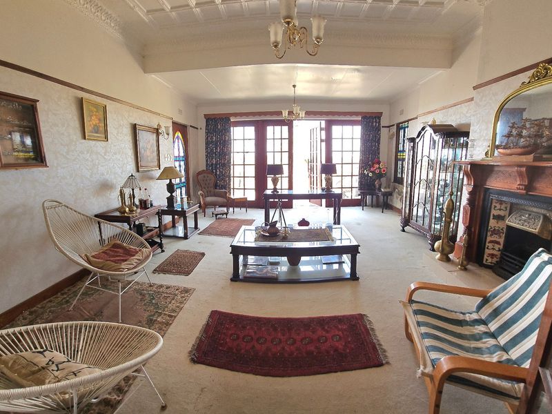 Spacious living room featuring a classic fireplace with timber mantel, ornate ceiling cornicing, and double french doors leading to the exterior.
