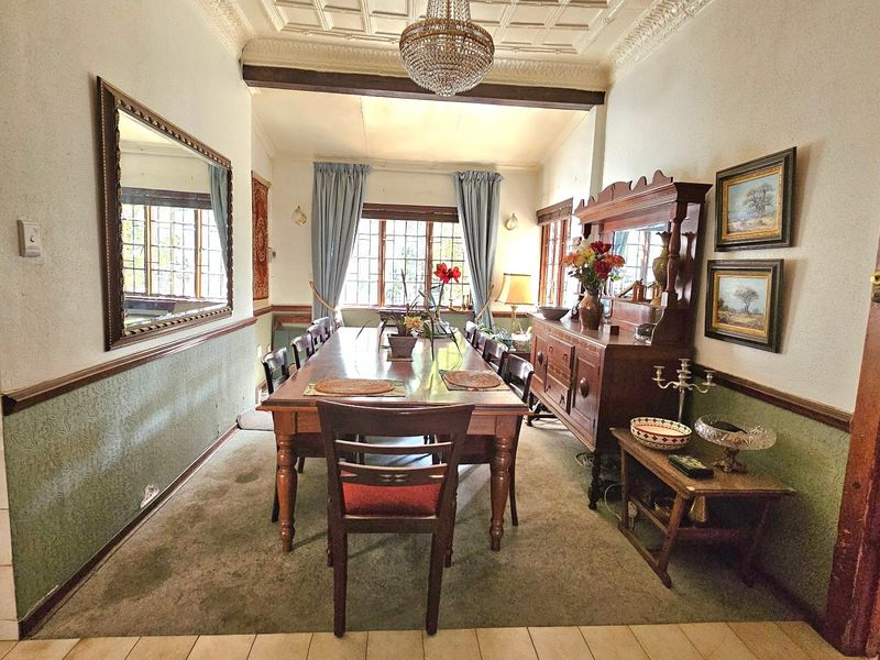 Formal dining room featuring a coffered ceiling, crown molding, wainscoting, and leaded glass windows, offering a classic architectural aesthetic.