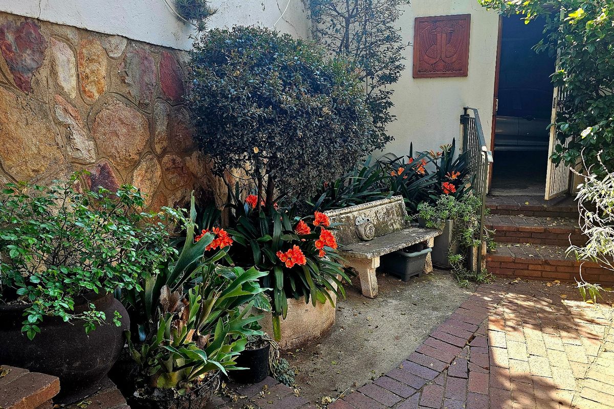A private rear courtyard area featuring stone-clad walls, brick paving, and concrete steps leading to the main dwelling entrance.