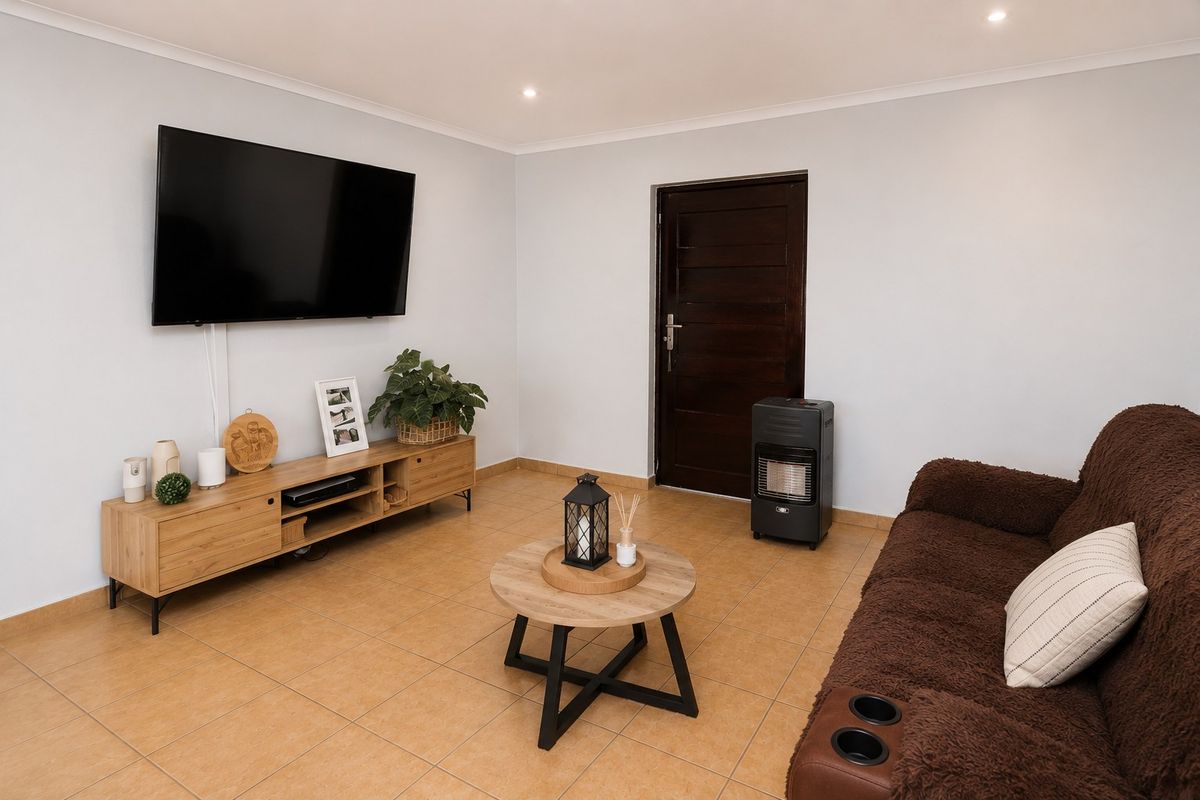 A well-maintained living room featuring neutral walls, tiled flooring, recessed downlighting, and a solid timber door.