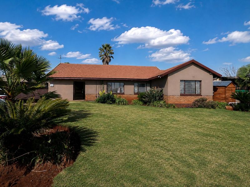A well-maintained single-story residential house featuring a terracotta tiled roof, brick and plaster facade, and established front garden.
