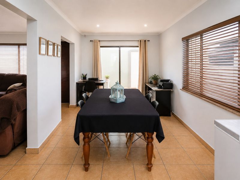 A bright dining area featuring tiled flooring, recessed lighting, and large windows with venetian blinds, providing access to the outdoor space via a sliding door.