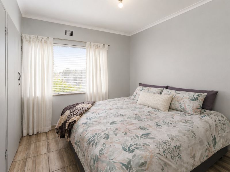 A well-maintained bedroom featuring neutral wall tones, tiled flooring, and built-in cupboards, offering a clean and functional living space.