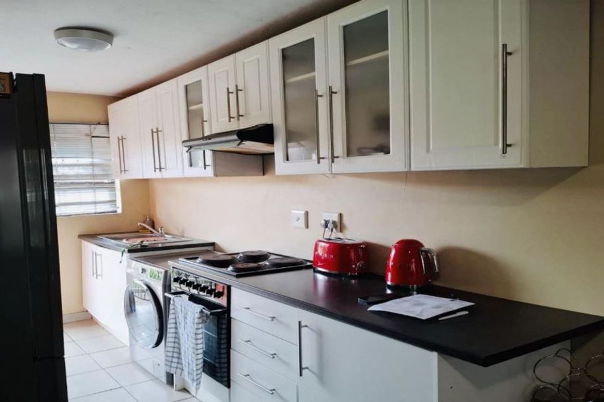 A functional kitchen featuring white cabinetry, dark countertops, an integrated oven and stove, and tiled flooring.