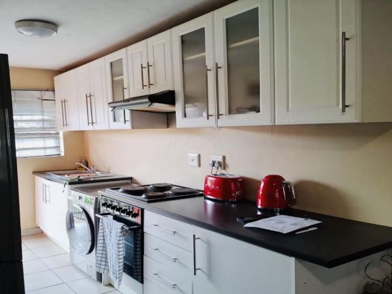 A functional kitchen featuring white cabinetry, dark countertops, an integrated oven and stove, and tiled flooring.